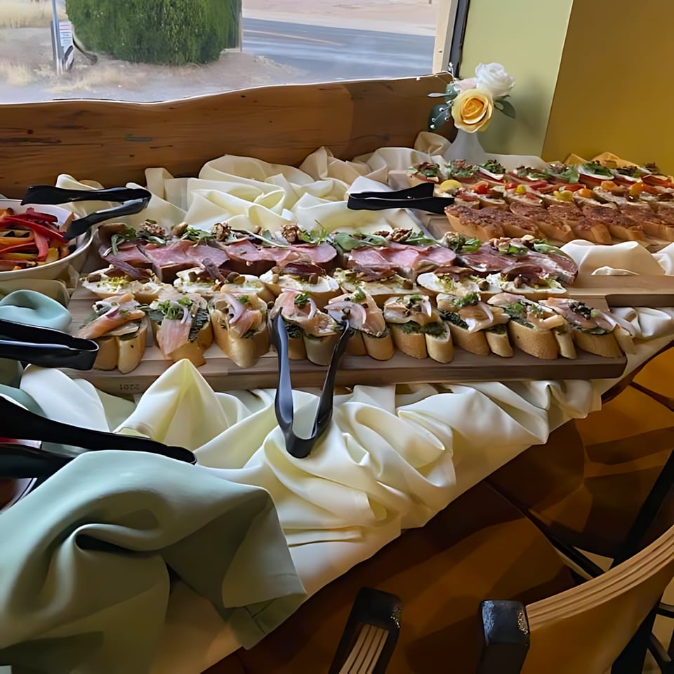 A buffet table laden with various European-style bruschetta and appetizers, with a window view.